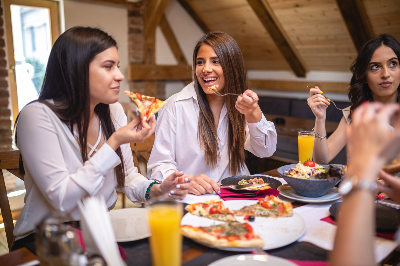 a group of women eating pizza at a restaurant